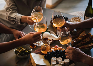 A group of people toasting wine at a table with food.