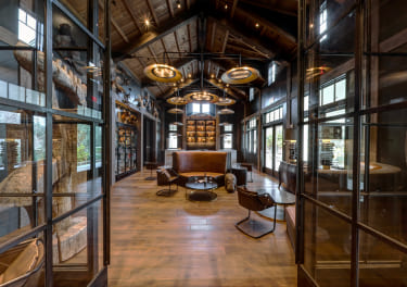 The lobby of a hotel with wooden floors and glass walls.
