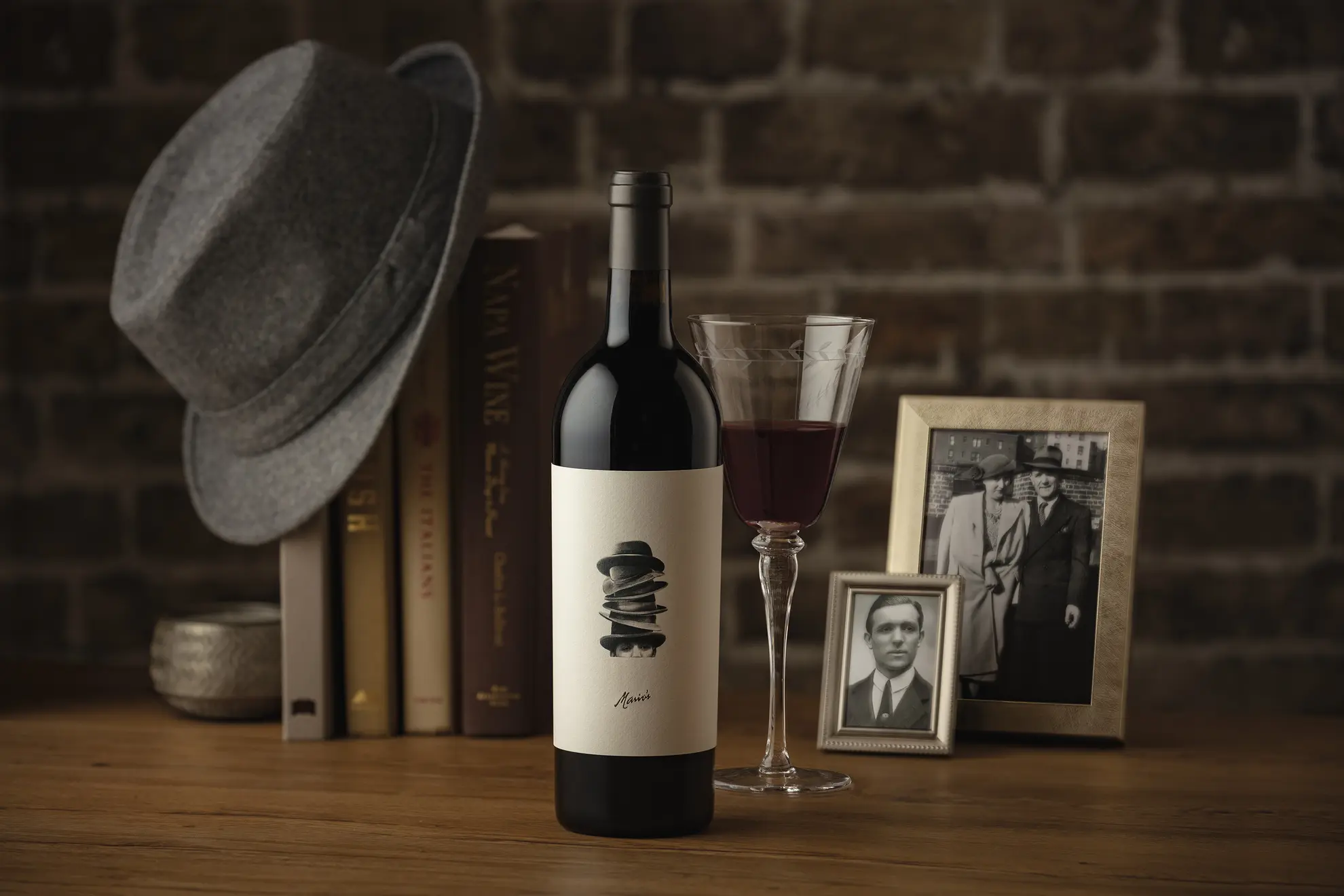 A bottle of wine sits on a table next to a hat.