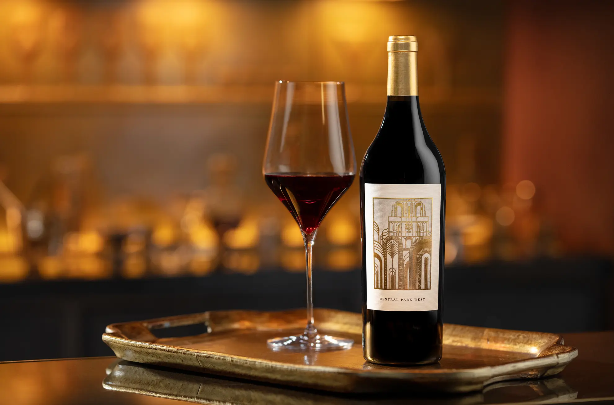 A bottle of wine and a glass on a tray.