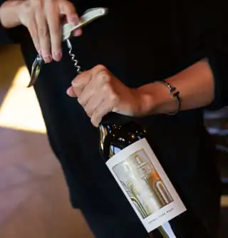 A person opening a bottle of wine.
