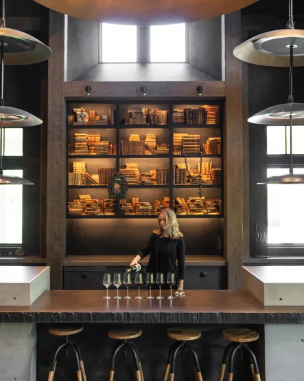 A woman standing at a bar in a wine cellar.