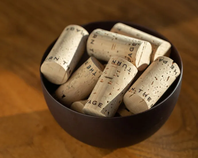 Wine corks in a bowl on a wooden table.