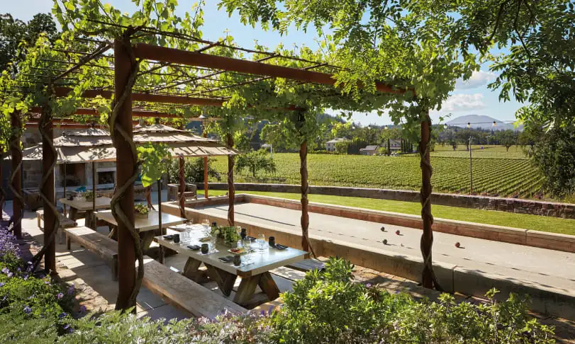 A patio with a table and chairs and a view of a vineyard.
