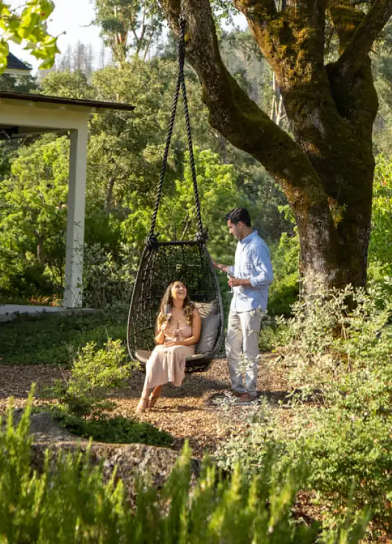 A couple sitting on a swing in a garden.