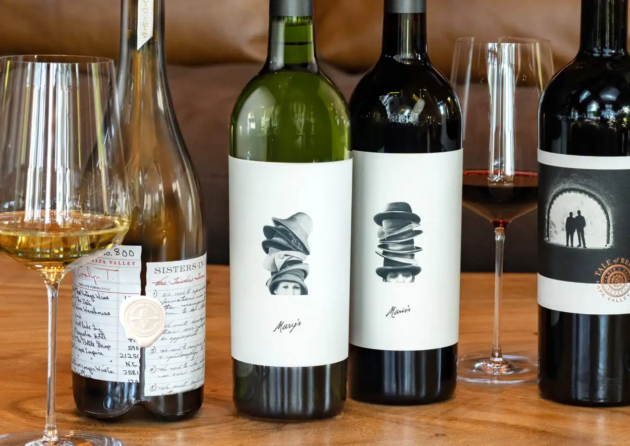 Four bottles of wine are lined up on a wooden table.